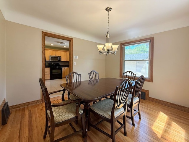 dining room featuring a chandelier, baseboards, and light wood-type flooring