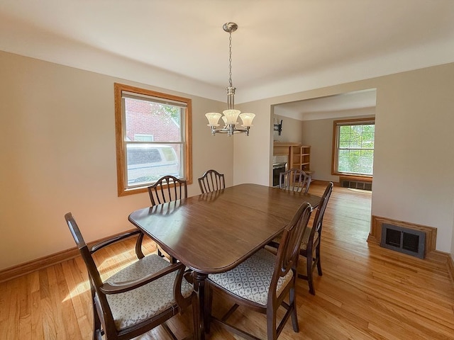dining room featuring a chandelier, light wood-style flooring, and baseboards