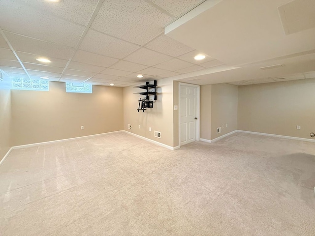below grade area featuring light carpet, recessed lighting, a drop ceiling, and baseboards