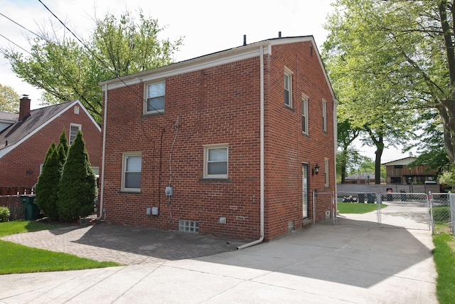 view of home's exterior featuring brick siding, fence, and a gate