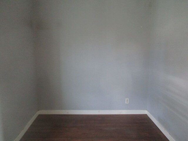 spare room with baseboards and wood finished floors