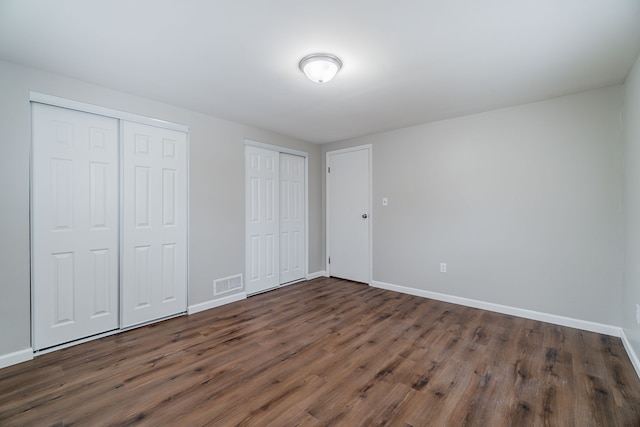 2040 Freeman St, Westland, MI 48186 - unfurnished bedroom with multiple closets, baseboards, dark wood-style floors, and visible vents