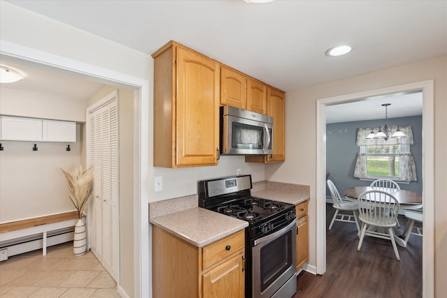kitchen with light countertops, stainless steel appliances, an inviting chandelier, and a baseboard heating unit