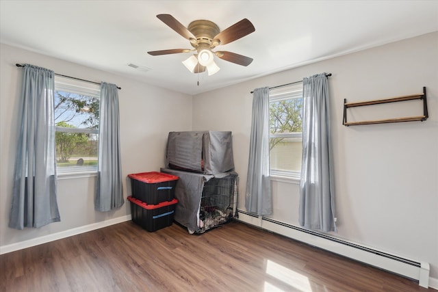 rec room featuring a healthy amount of sunlight, baseboards, a baseboard radiator, and wood finished floors