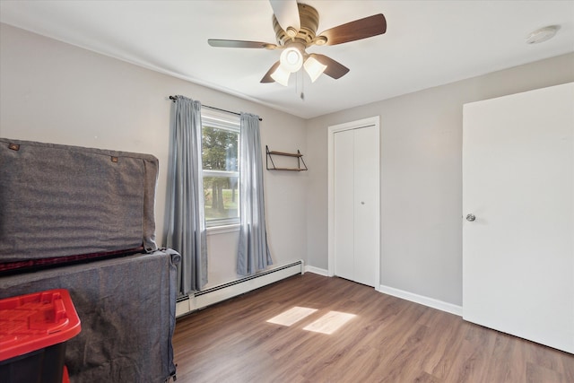 unfurnished bedroom with baseboards, ceiling fan, wood finished floors, and a baseboard radiator