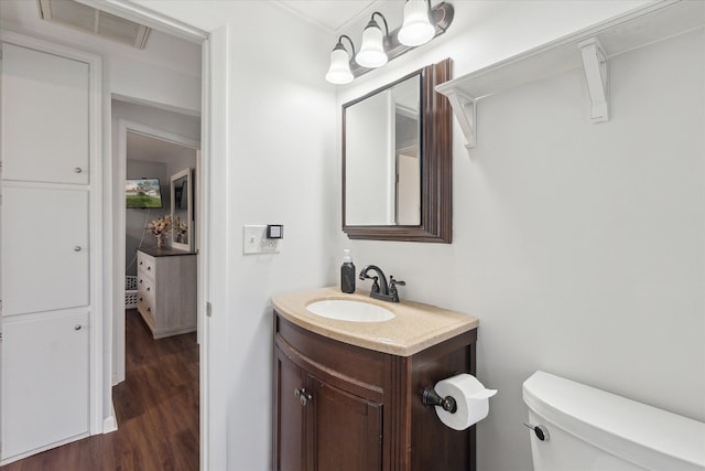 bathroom featuring vanity, toilet, wood finished floors, and visible vents