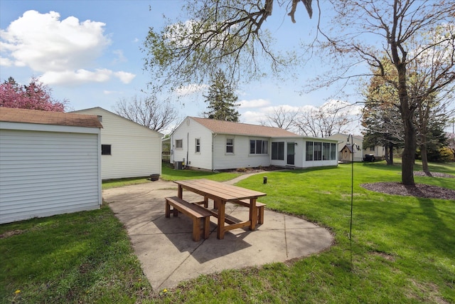 rear view of house with a sunroom, a patio, and a yard