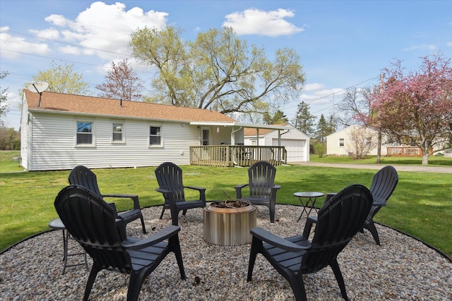 back of house featuring a lawn, a garage, a fire pit, and a wooden deck
