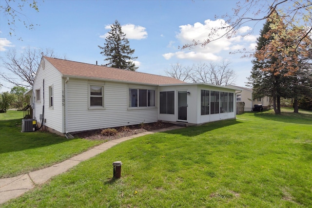 back of property with roof with shingles, a yard, a sunroom, and central AC