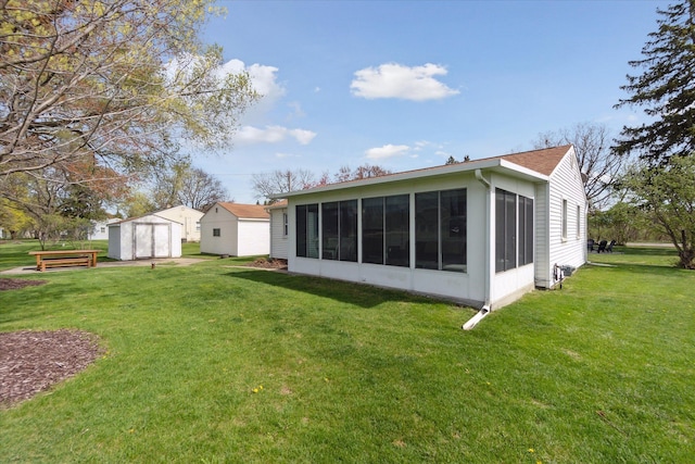 back of house featuring a storage shed, a detached garage, a sunroom, an outbuilding, and a yard