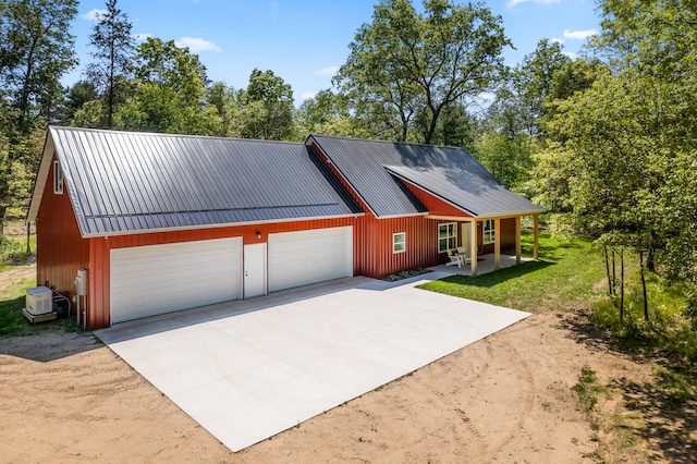 view of front of house featuring a garage, a porch, driveway, and metal roof
