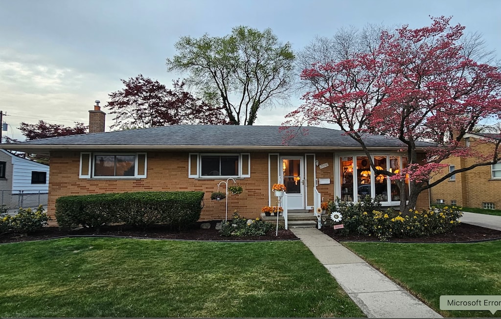 ranch-style house with a chimney, brick siding, a front yard, and entry steps