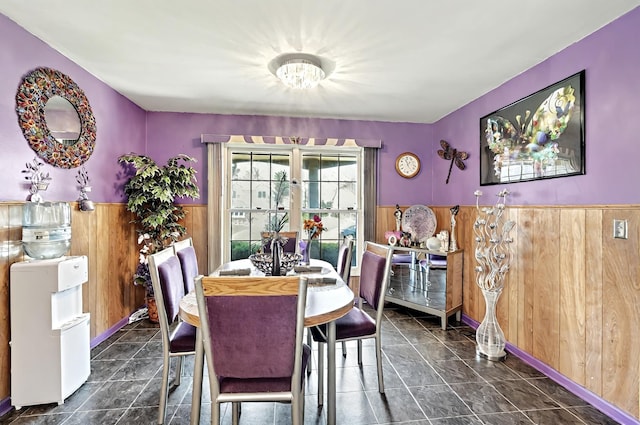dining space featuring an inviting chandelier, wainscoting, and wood walls