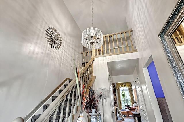 stairs with an inviting chandelier and a towering ceiling