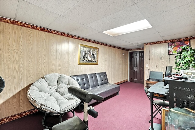 carpeted living area featuring wood walls and a paneled ceiling