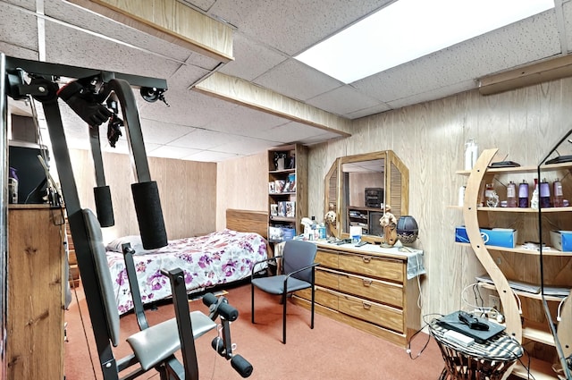 bedroom with carpet, a paneled ceiling, and wooden walls