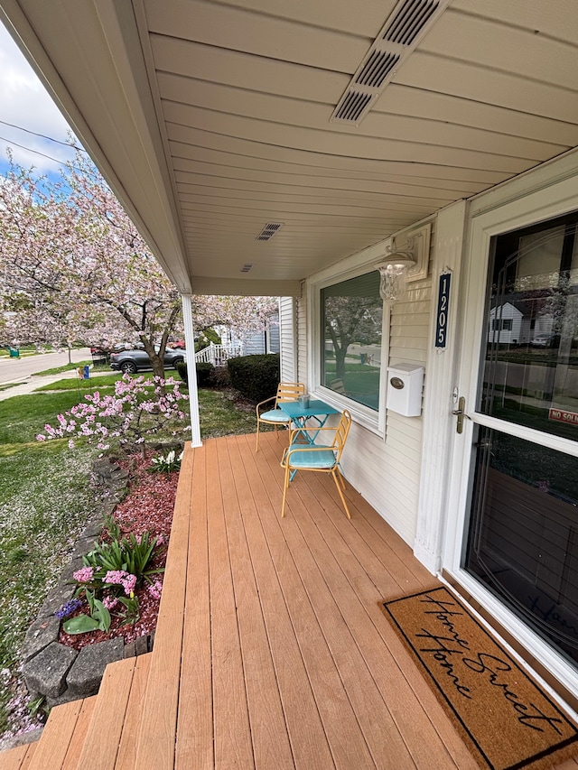 wooden terrace featuring a porch and visible vents