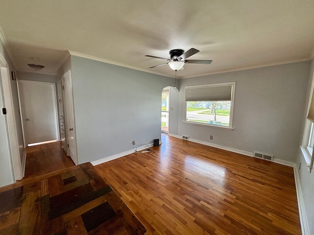 empty room with visible vents, arched walkways, ceiling fan, and wood finished floors