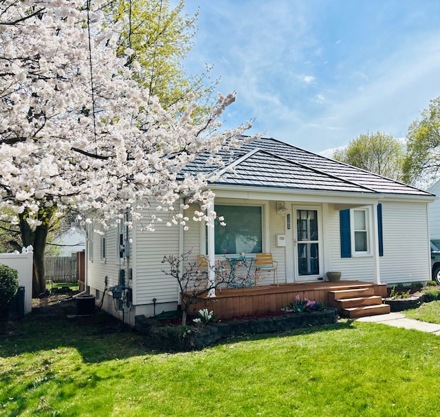 bungalow-style house with a porch, a front lawn, central AC, and fence
