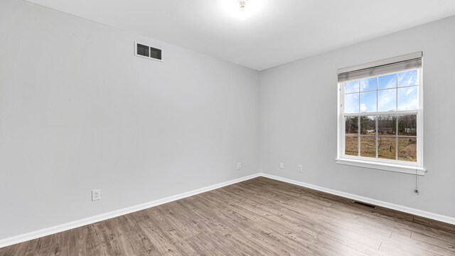empty room with baseboards, wood finished floors, and visible vents
