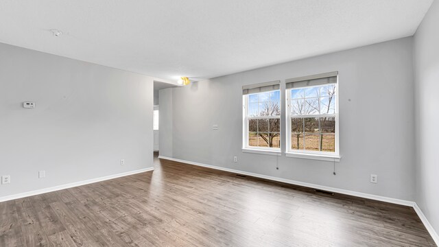 unfurnished room featuring baseboards, wood finished floors, and visible vents