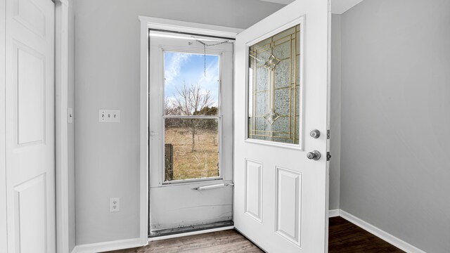 doorway to outside featuring baseboards and wood finished floors