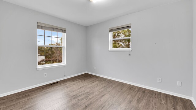 spare room featuring visible vents, a healthy amount of sunlight, and wood finished floors