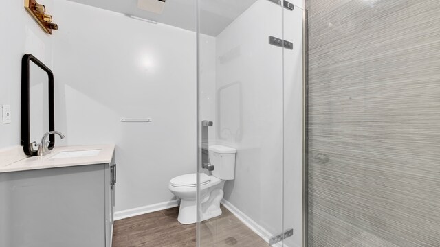 bathroom featuring vanity, toilet, baseboards, a shower stall, and wood finished floors