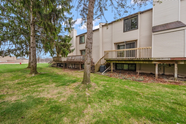 rear view of house featuring a lawn, a wooden deck, and stairs