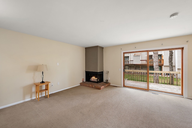 unfurnished living room featuring a multi sided fireplace, baseboards, carpet flooring, and visible vents