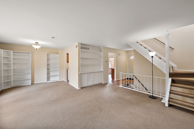 unfurnished living room featuring baseboards, visible vents, and carpet