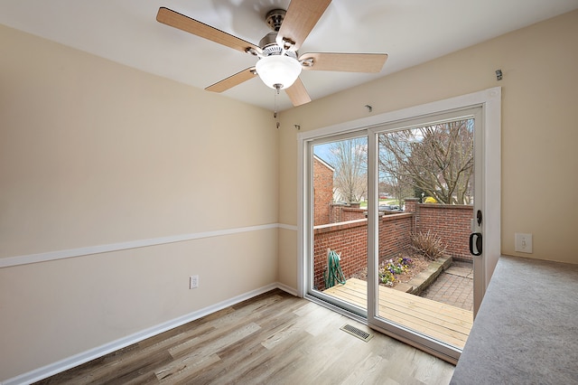 empty room featuring a ceiling fan, wood finished floors, and visible vents