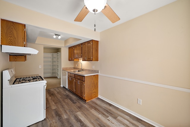 kitchen featuring exhaust hood, a ceiling fan, a sink, white appliances, and dark wood-type flooring