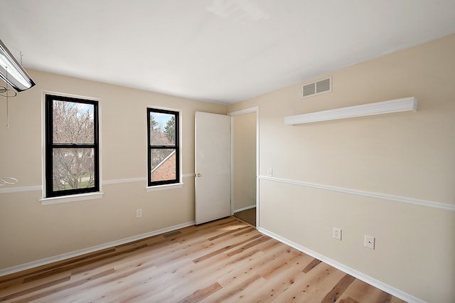 spare room with light wood-style floors, baseboards, and visible vents