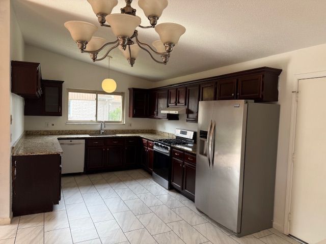 kitchen with a notable chandelier, a sink, marble finish floor, stainless steel appliances, and under cabinet range hood