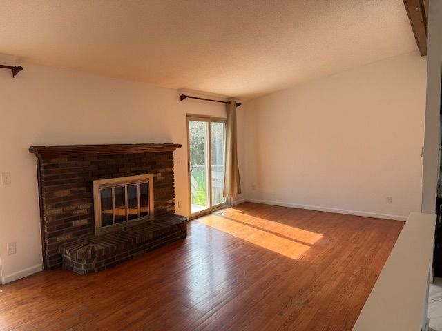 unfurnished living room with baseboards, wood finished floors, and a fireplace