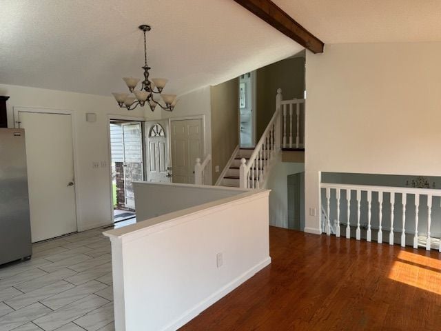 kitchen featuring vaulted ceiling with beams, freestanding refrigerator, pendant lighting, and a notable chandelier
