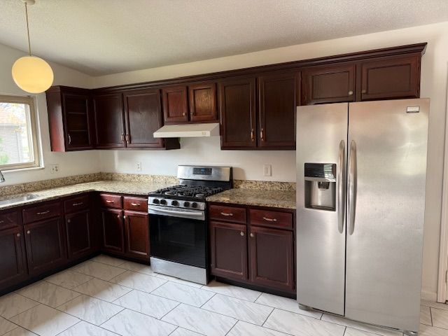 kitchen with light stone counters, a sink, under cabinet range hood, and stainless steel appliances