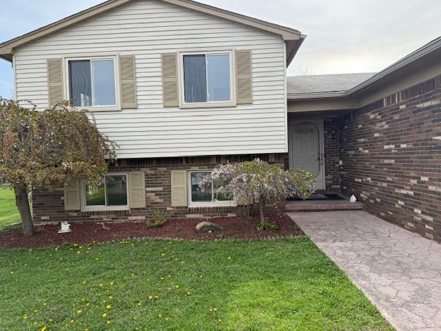 view of front facade featuring brick siding and a front lawn