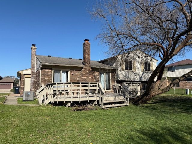 back of property with central air condition unit, a wooden deck, a yard, and a chimney