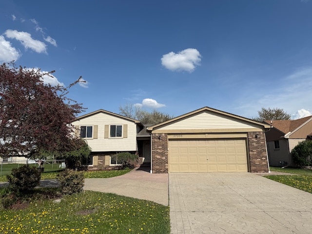 tri-level home featuring brick siding, a garage, and driveway