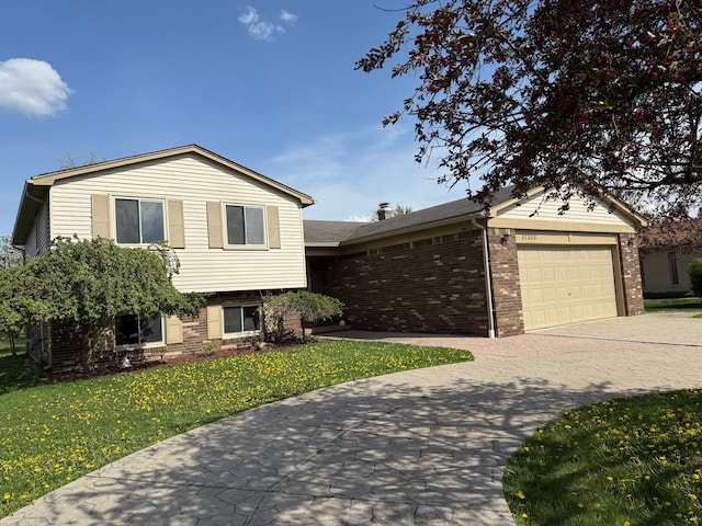 tri-level home featuring an attached garage, a front yard, driveway, and brick siding
