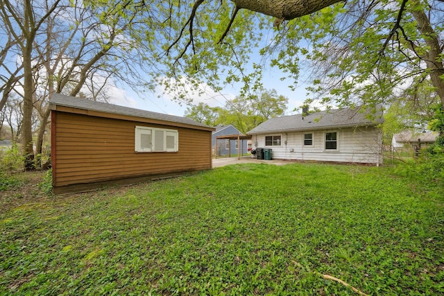 rear view of house with a yard, a patio, an outbuilding, and central AC unit
