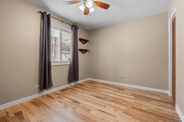 spare room with a ceiling fan, baseboards, visible vents, and light wood finished floors