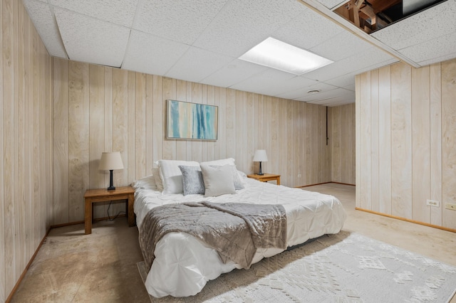 bedroom featuring baseboards, wood walls, and a paneled ceiling