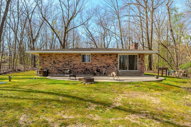 back of property featuring a patio, brick siding, a yard, and a chimney