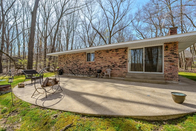 back of house featuring entry steps, a chimney, a patio area, and brick siding