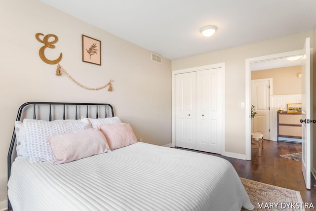 bedroom featuring baseboards, a closet, dark wood finished floors, and visible vents