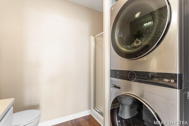 washroom featuring baseboards, laundry area, dark wood-style floors, and stacked washer / dryer