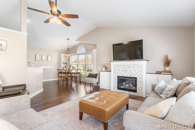 living room featuring wood finished floors, a fireplace, baseboards, high vaulted ceiling, and a ceiling fan